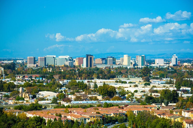 Vista of the San Jose skyline, with puffy clouds in the background and residential areas in the foreground.