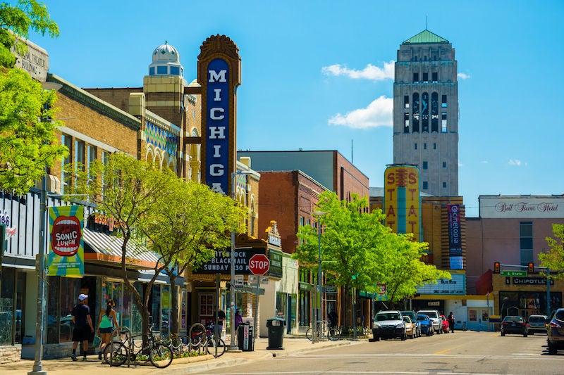 Ann Arbor, United States - May 25, 2014: Scene from Downtown Ann Arbor, Michigan, with shops, pedestrians walking, a theater, and a bell tower from the University of Michigan being shown.