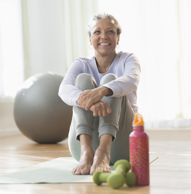 Older hispanic woman sitting on exercise mat